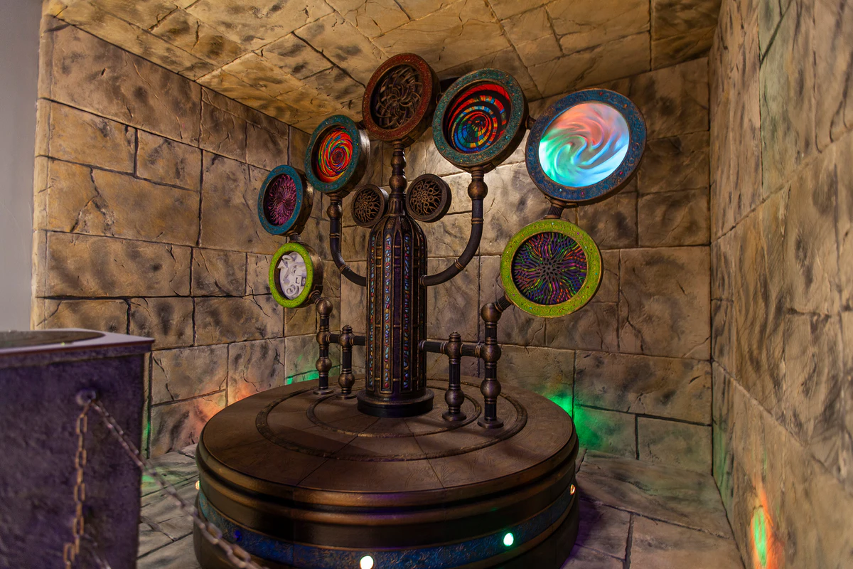 Steampunkowa maszyna z kolorowymi tarczami w scenografii z kamiennymi ścianami